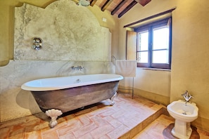 A bathroom with a clawfoot bathtub, a bidet, and a window with curtains. - Col Di Forche (Monterchi)