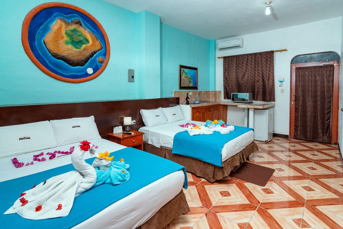 A hotel room with two beds, a desk, a computer, and a large painting on the wall.