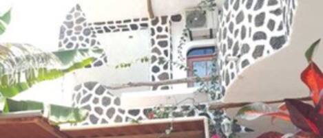 A building with a unique giraffe-patterned facade, outdoor seating with a table and chairs, and a potted plant.