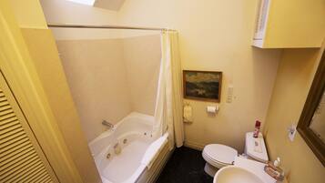 Un baño con bañera, inodoro y un cuadro en la pared.
