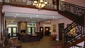 A spacious lobby with a stone fireplace, comfortable seating, and a grand staircase. - Hearthstone Elegant Lodge by the River (Kamiah)
