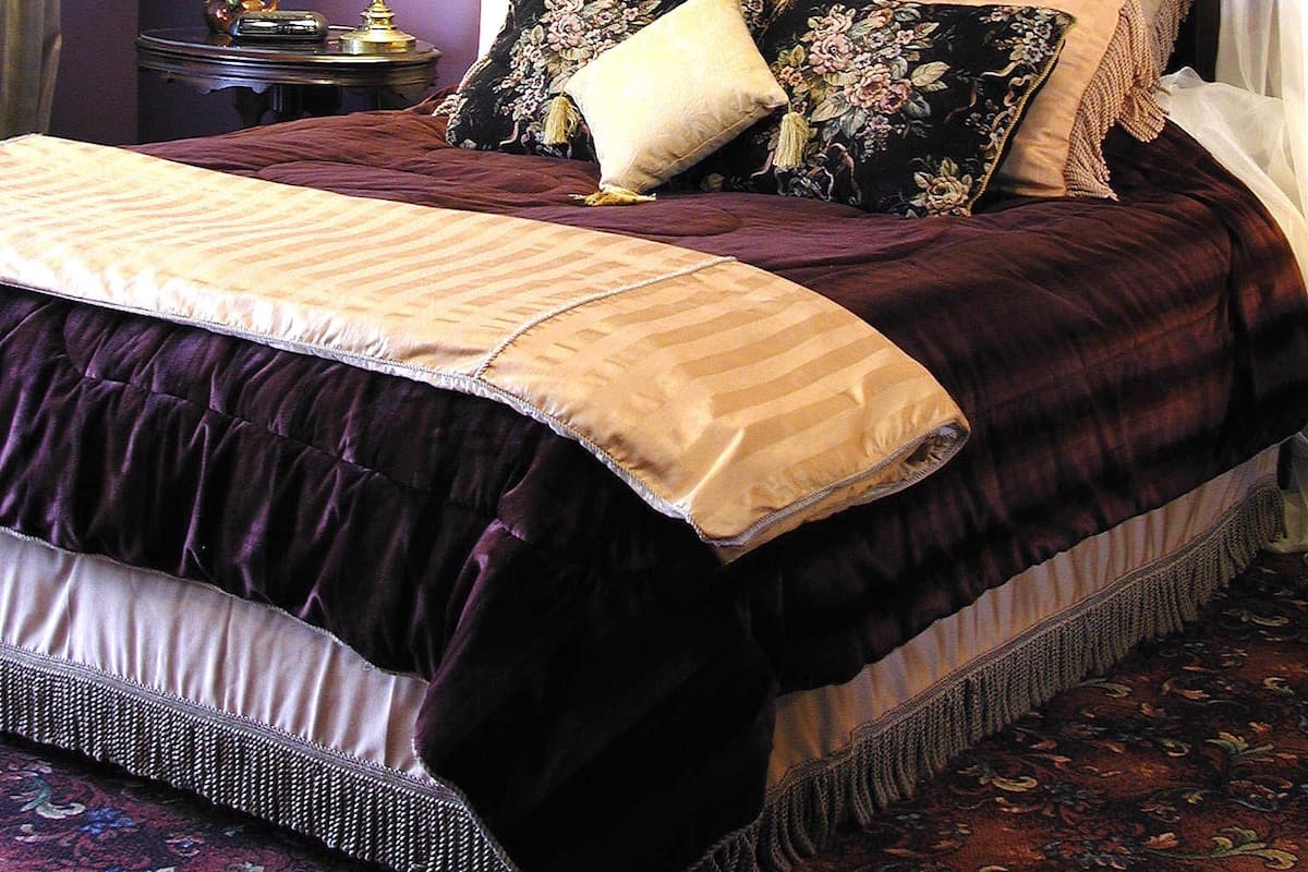 A bedroom with a large bed, ornate headboard, and a framed picture on the wall.
