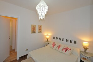Una camera da letto con un letto, due abat-jour, un lampadario e una parete con la scritta 'BONHEUR'.