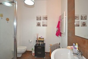 A bathroom with a shower, toilet, sink, and a mirror with pictures. - Mariasole (Castiglione della Pescaia)