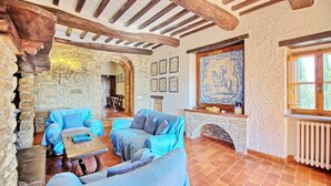 A rustic interior with stone walls, wooden beams, a fireplace, and traditional decor. - Uccellaia (Magione)