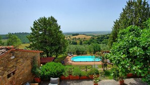 A stone building with a pool, outdoor seating, and a view of the countryside. - Uccellaia (Magione)