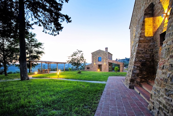 A stone building with a covered outdoor seating area and a view of a body of water.