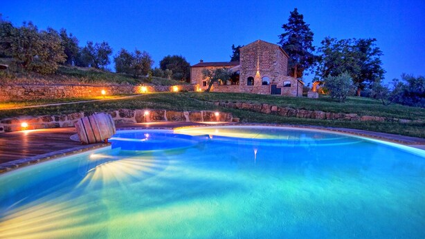 A swimming pool with a stone building in the background. - Villa Ferdinando (Poggibonsi)