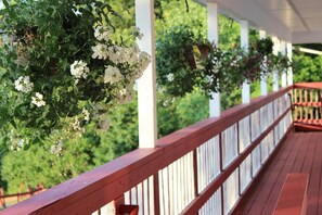 Una terraza de madera con barandas blancas y cestas de flores colgantes.