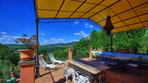 An outdoor patio with a table and chairs, surrounded by potted plants and overlooking a scenic landscape. - Casa Vania (Reggello)