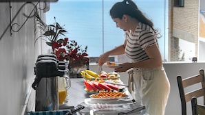 Une personne qui sert des fruits à une table offrant une vue sur la mer.