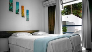 Une chambre d’hôtel avec un lit, une fenêtre avec des rideaux et un mur décoré d’œuvres d’art.