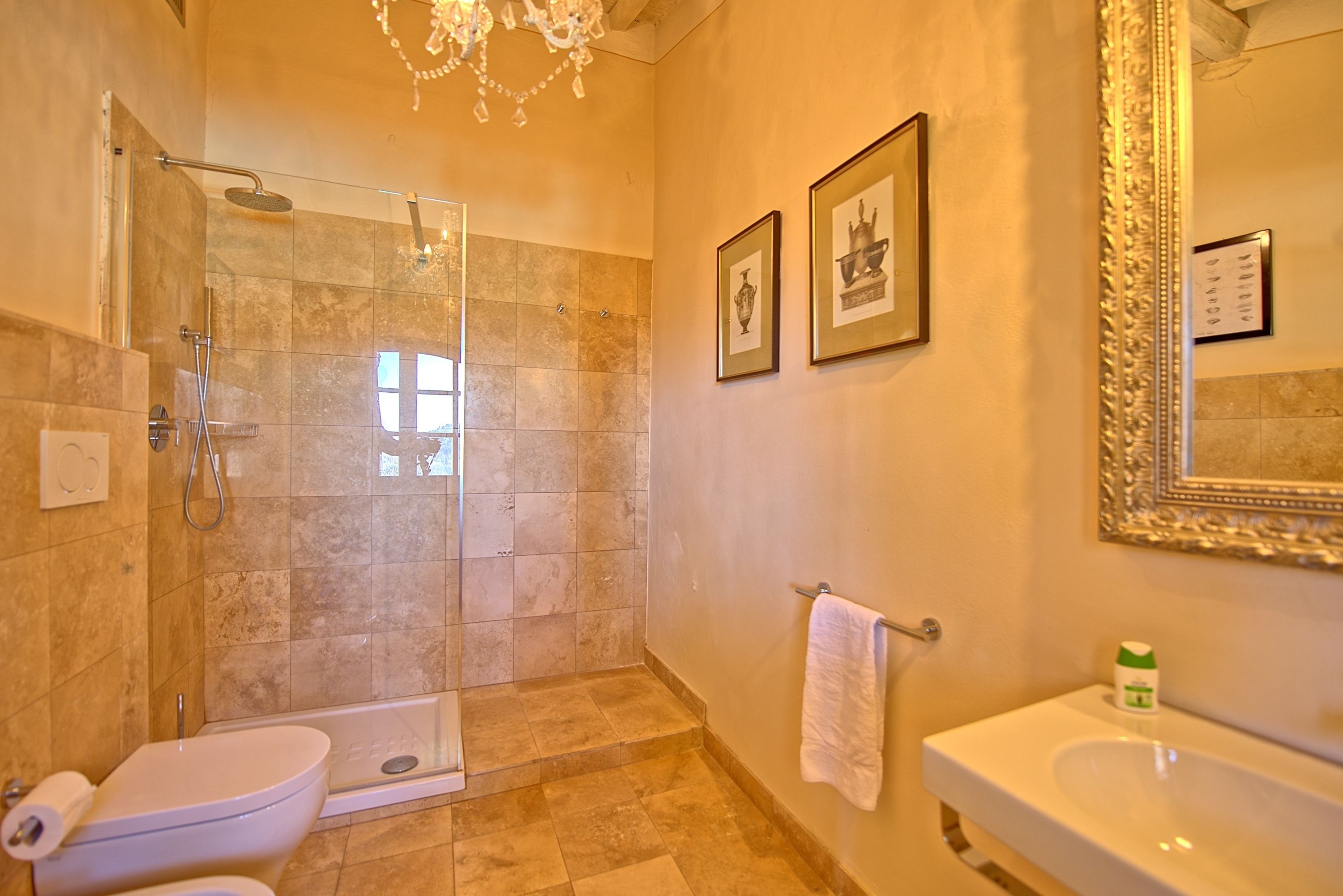 Ein Badezimmer mit Duschkabine, Toilette, Waschbecken und gerahmten Bildern an der Wand.
