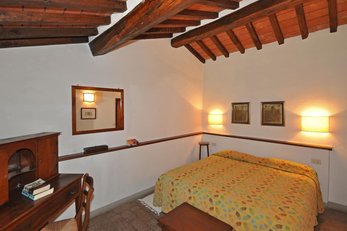 Un dormitorio con cama, escritorio de madera y espejo.