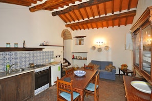 A kitchen with a wooden table, chairs, and a blue and white tiled backsplash. - Borgo Del Castagno (Cortona)