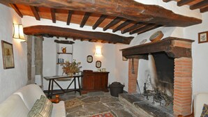 A rustic interior with exposed wooden beams, a stone fireplace, and traditional furnishings. - Borgo Del Castagno (Cortona)