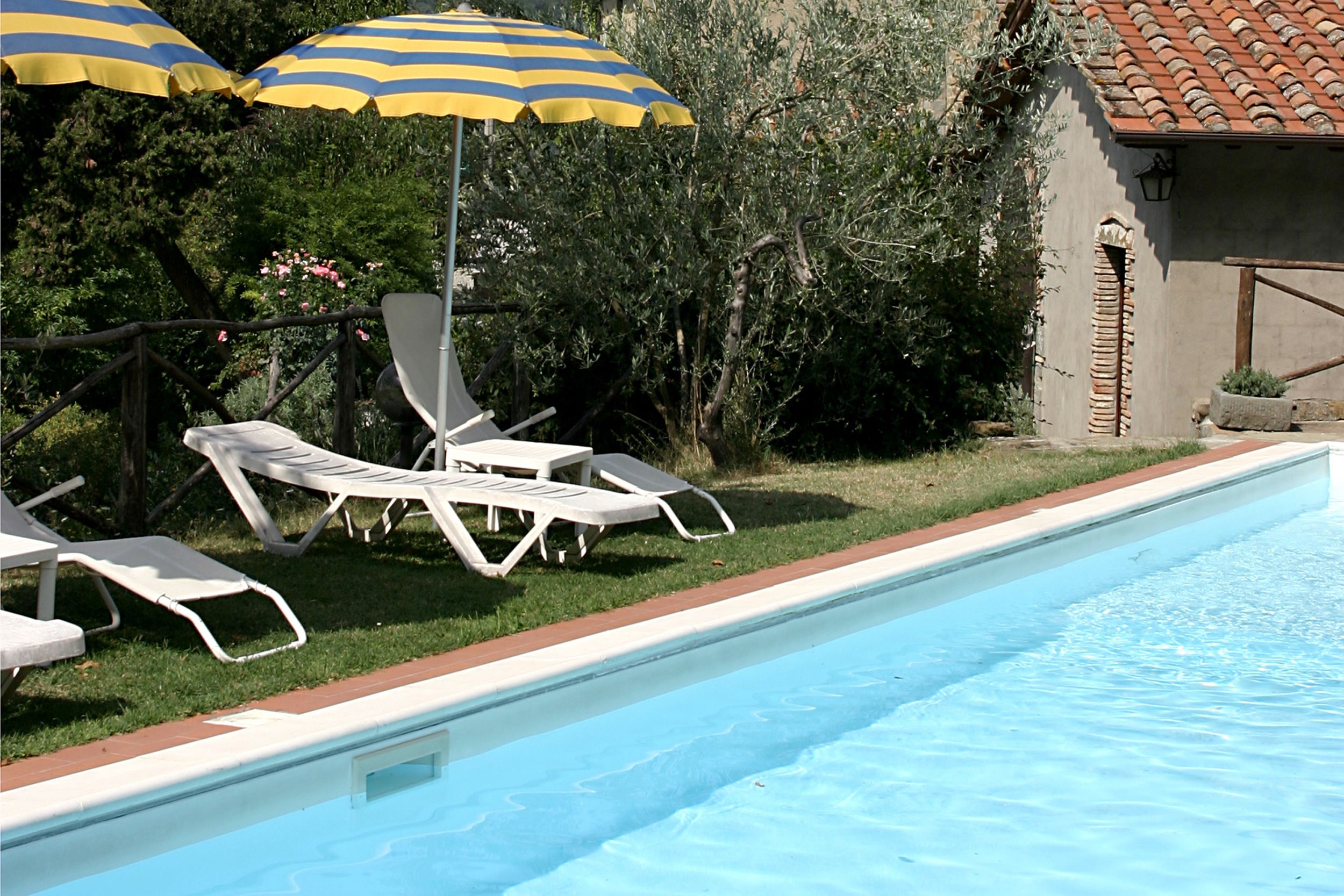 Una piscina con sillas de descanso y sombrillas a rayas.