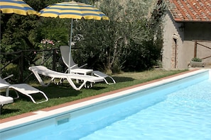 A swimming pool with lounge chairs and striped umbrellas. - Borgo Del Castagno (Cortona)