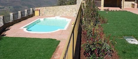 A swimming pool with a stone wall and a view of mountains.