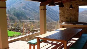 Mesa y bancos de madera en un balcón con vistas a la montaña.