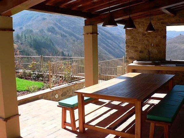 A wooden table and benches on a balcony with a mountain view.