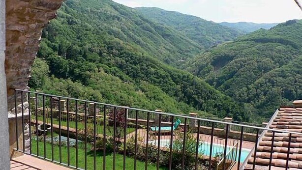 Un balcón con vistas a colinas verdes exuberantes y una zona de piscina.