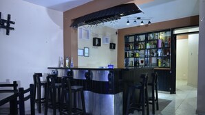 A bar area with a counter, stools, and a shelf of bottles. - Matryoshka (Ica)