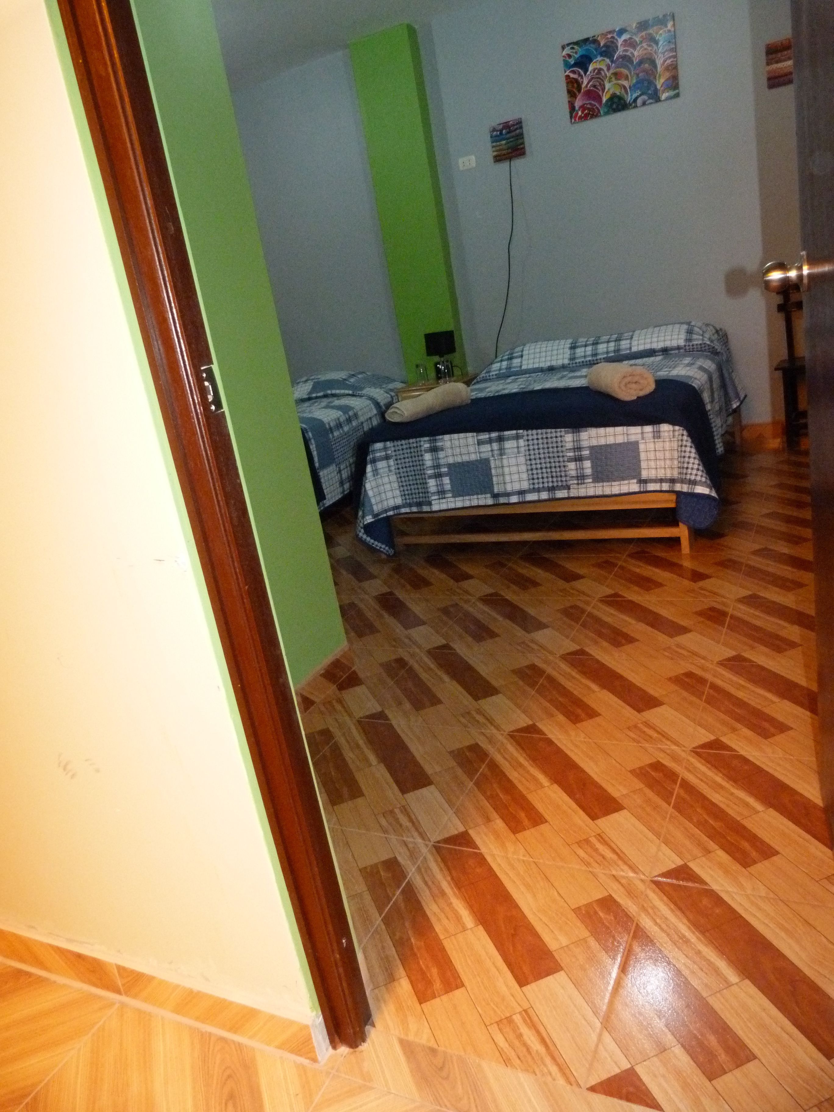 Una habitación con dos camas, una pared verde y suelo de madera.