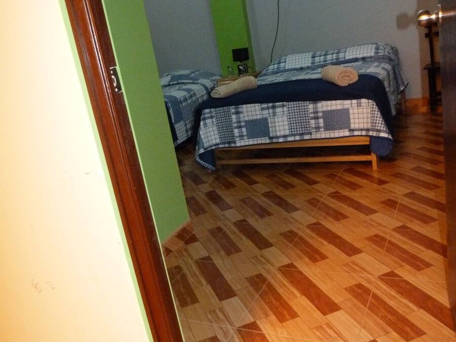 Una habitación con dos camas, una pared verde y suelo de madera.