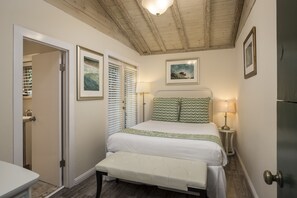 A bedroom with a bed, bench, bedside lamps, and framed artwork on the walls.