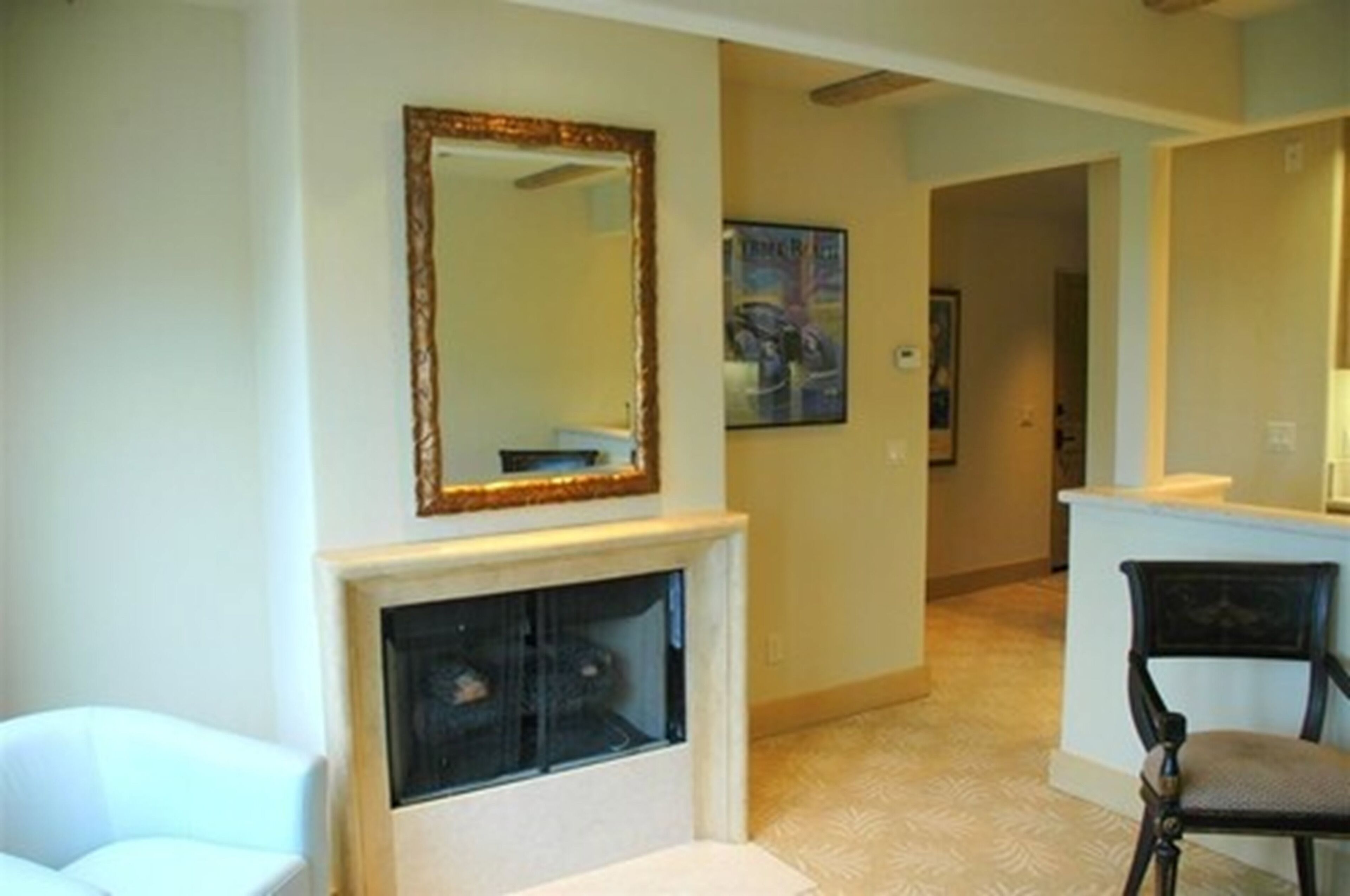 A living room with a fireplace, a large mirror, and a framed picture on the wall.