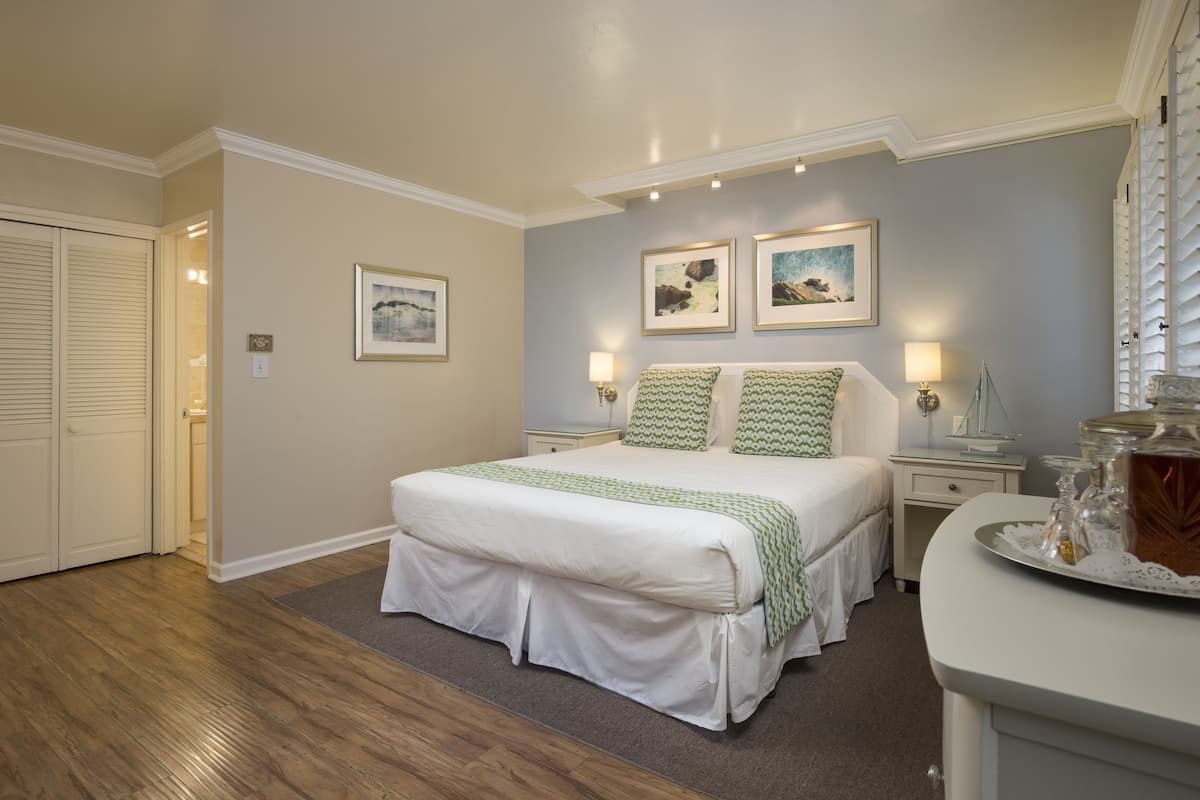 A bedroom with a large bed, two bedside tables, a nightstand, and a dresser.