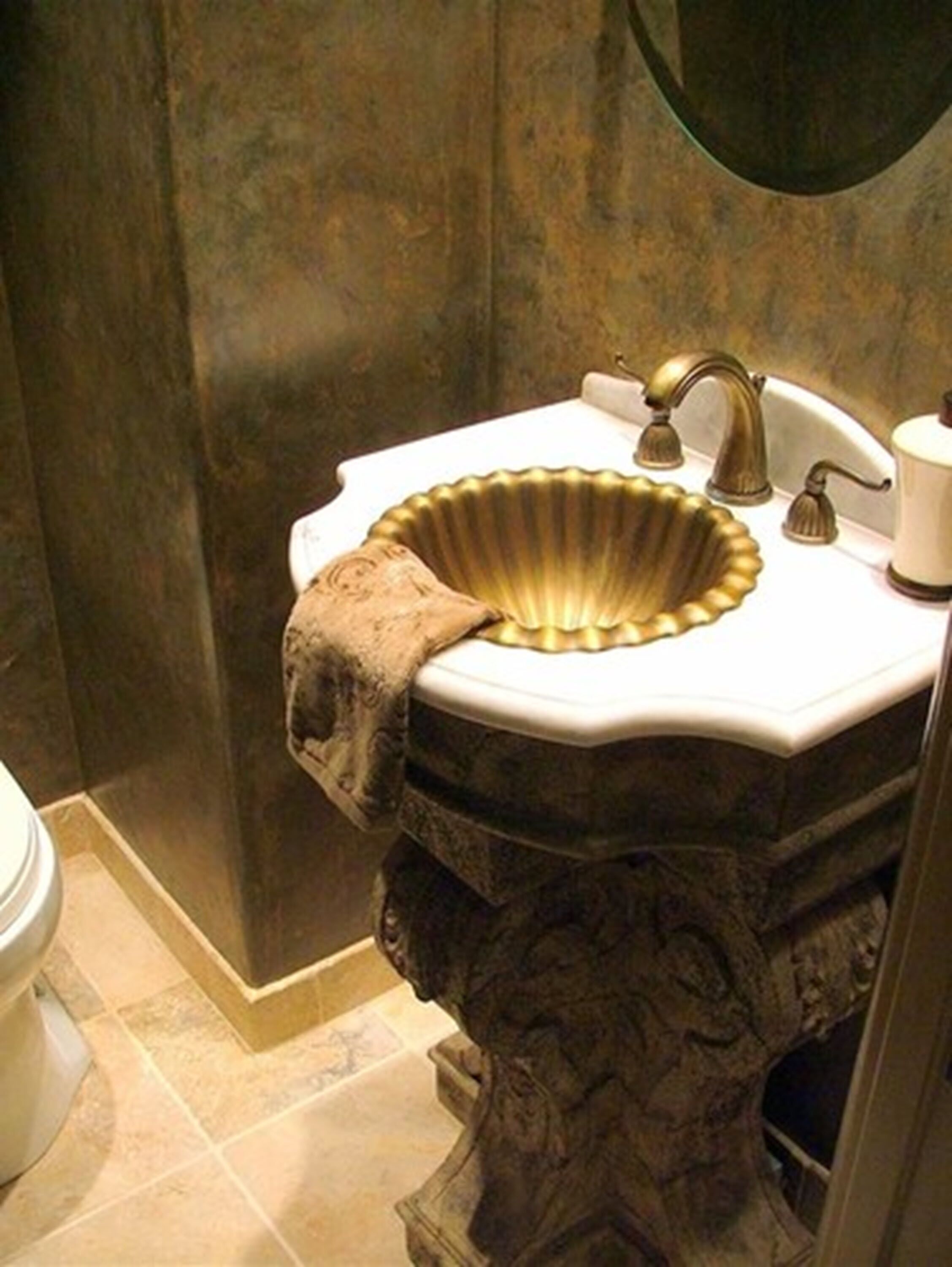 A bathroom with a gold-colored sink, a towel, and a mirror above the sink.