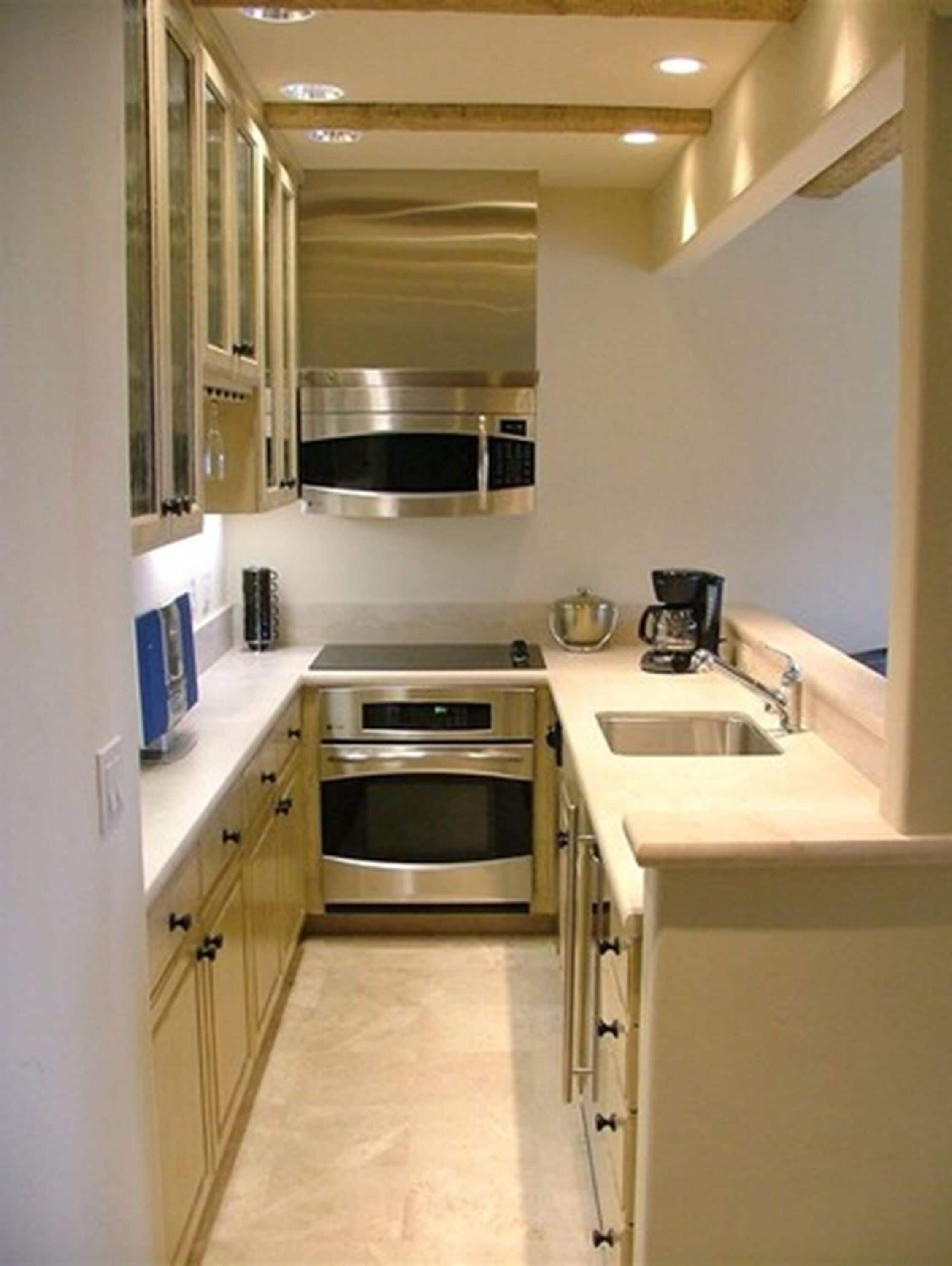 A compact kitchen with stainless steel appliances, a built-in oven, and a coffee maker.