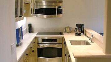 A compact kitchen with stainless steel appliances, a built-in oven, and a coffee maker.