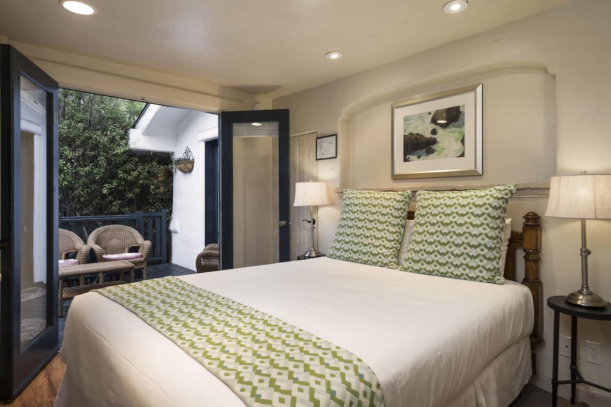 A bedroom with a large bed, two pillows, a nightstand, a lamp, and a framed picture on the wall.