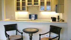 A kitchen with wooden cabinets, a sink, and a small round table with two chairs. - Monte Verde Inn (Carmel)