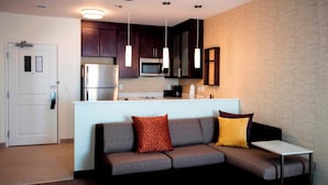 A modern kitchen with dark cabinets, stainless steel appliances, pendant lighting, and a built-in microwave. - Residence Inn Lake Charles (Lake Charles)