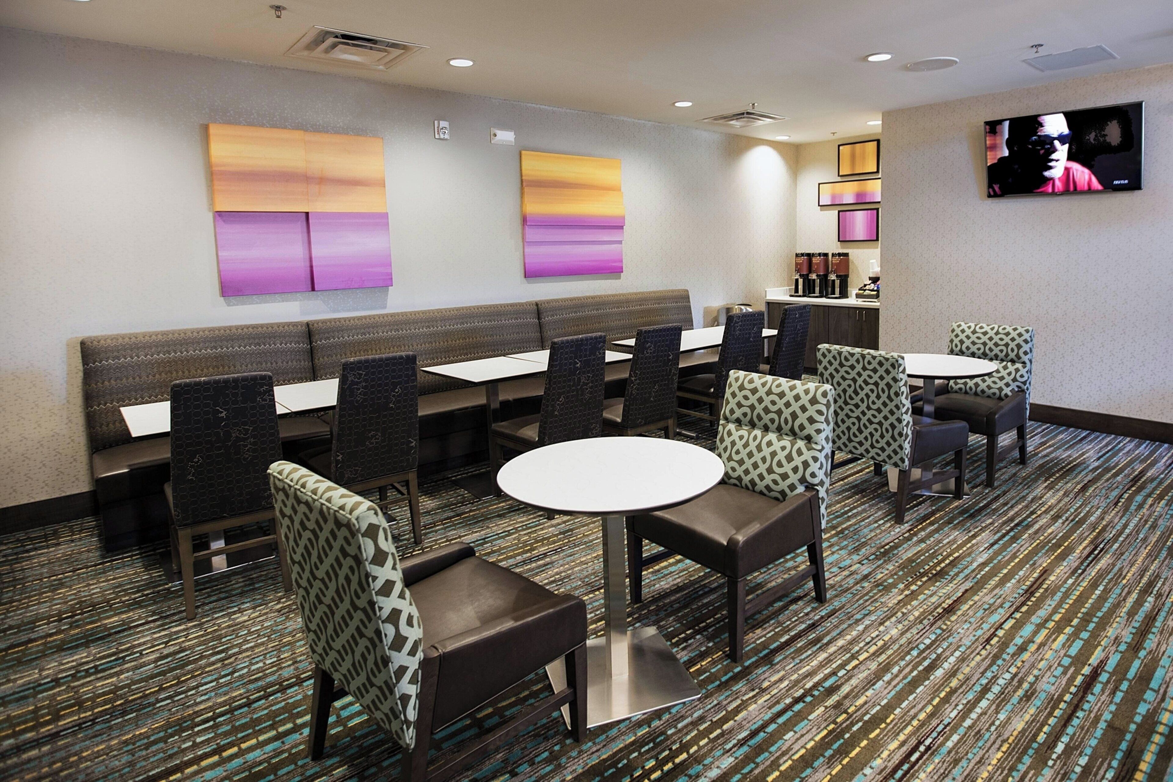 A hotel dining area with booths, tables, and patterned chairs.
