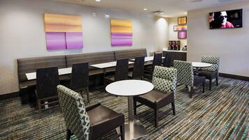 A hotel dining area with booths, tables, and patterned chairs.