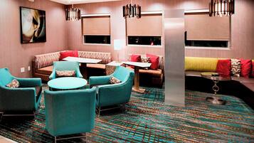 A modern hotel lobby with seating areas, a patterned carpet, and contemporary lighting fixtures.
