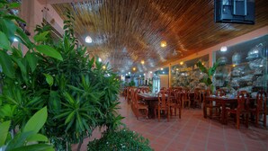 A restaurant with bamboo ceiling, green plants, and wooden tables and chairs. - Serkirin Mary Angkor Villa (Siem Reap)