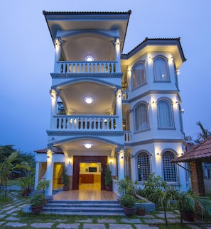 A multi-story building with a grand entrance, multiple balconies, and a well-lit facade.