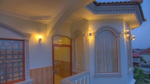 A staircase with a wooden handrail and a white balustrade, leading to a landing with a glass door and a wooden door. - Serkirin Mary Angkor Villa (Siem Reap)