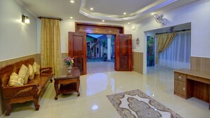 A spacious living area with a wooden sofa, a coffee table, and a desk. - Serkirin Mary Angkor Villa (Siem Reap)