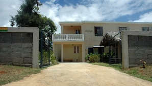 A two-story building with a balcony, a gate, and a small garden area. - Reve des Iles (Rodrigues Island)