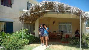 A covered outdoor area with a thatched roof, potted plants, and a motorcycle parked nearby. - Reve des Iles (Rodrigues Island)