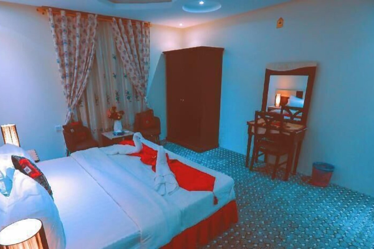 A bedroom with a bed, a desk, a chair, and a wardrobe.