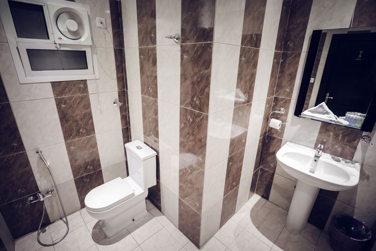 A bathroom with a toilet, bidet, sink, and mirror.
