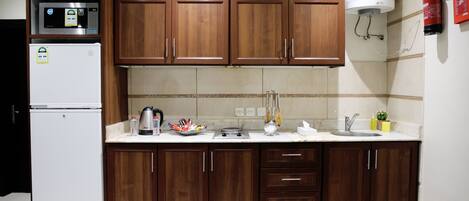 A kitchen with wooden cabinets, a white refrigerator, a stove, and a water heater.